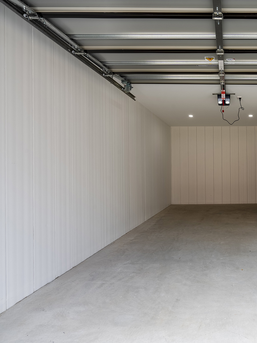 AFS Rediwall Basement Wall Rediwall basement walls unpainted with concrete floor and garage roller door.